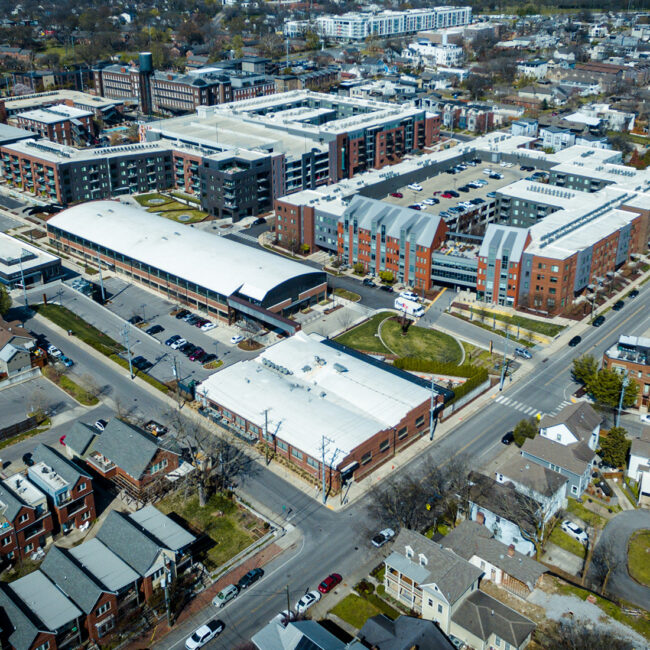 Aerial view of a dense urban redevelopment featuring large multi-story residential and commercial buildings, modern infrastructure, and structured parking within a surrounding historic neighborhood fabric.