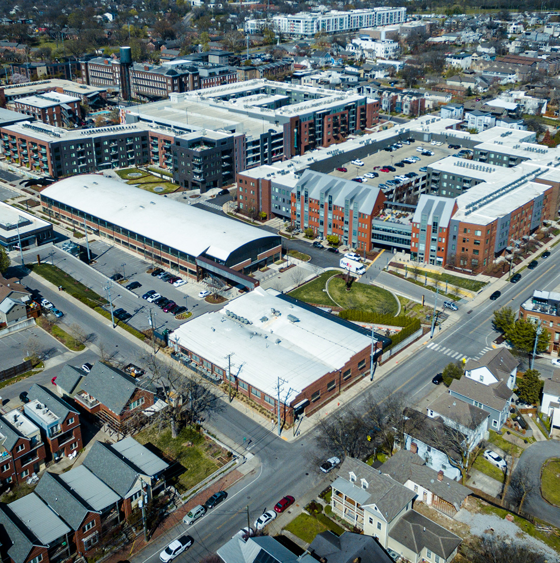 Aerial view of a dense urban redevelopment featuring large multi-story residential and commercial buildings, modern infrastructure, and structured parking within a surrounding historic neighborhood fabric.